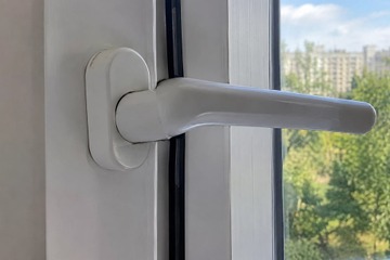 Белая ручка пластикового окна крупным планом
